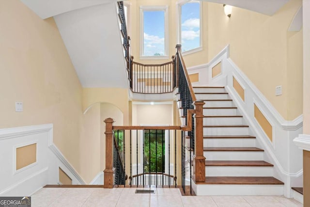 staircase featuring a towering ceiling and tile patterned flooring