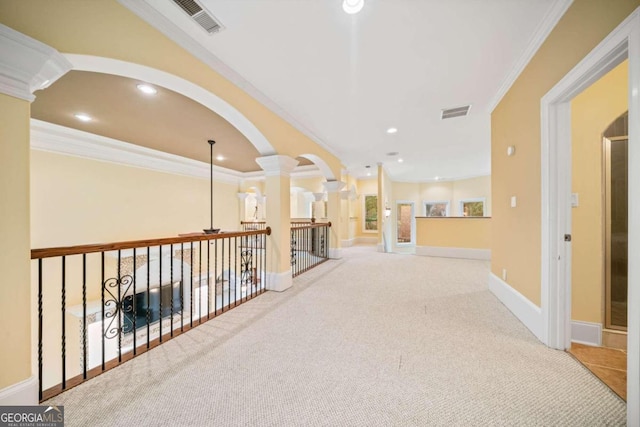 hall featuring crown molding, light colored carpet, and ornate columns