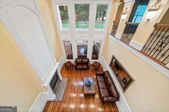 living room with wood-type flooring, a high ceiling, and a tile fireplace