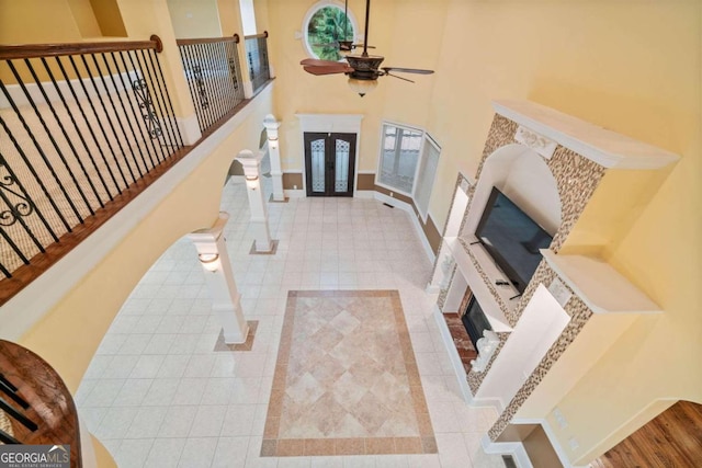 tiled living room with ceiling fan and a high ceiling