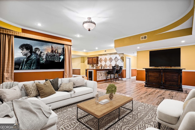 living room with beverage cooler, light hardwood / wood-style floors, and ornamental molding