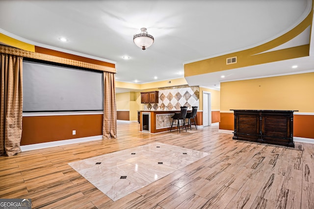 home theater with decorative columns, crown molding, and light hardwood / wood-style floors