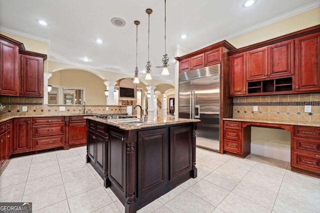 kitchen featuring backsplash, appliances with stainless steel finishes, hanging light fixtures, and ornate columns