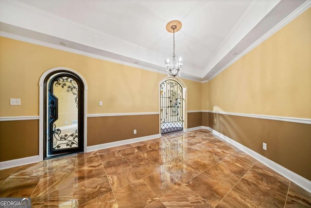 foyer entrance with a tray ceiling, ornamental molding, and a chandelier