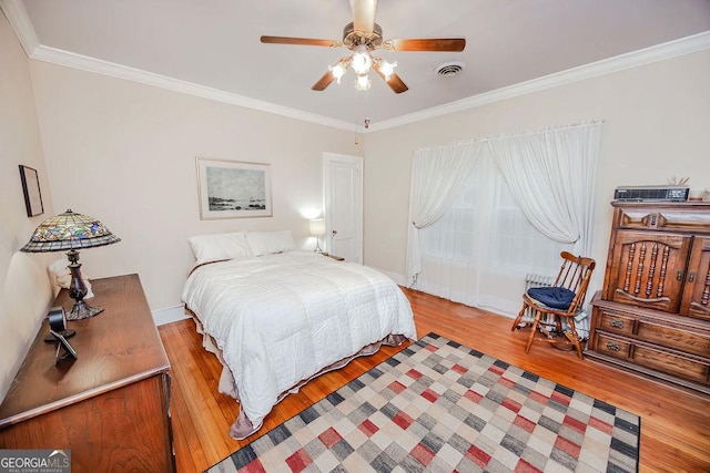 bedroom featuring light hardwood / wood-style flooring, ceiling fan, and crown molding