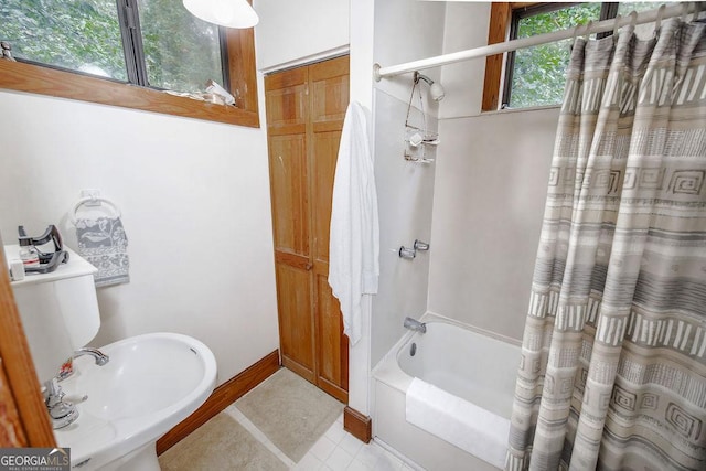 bathroom with sink, shower / bathtub combination with curtain, and a healthy amount of sunlight