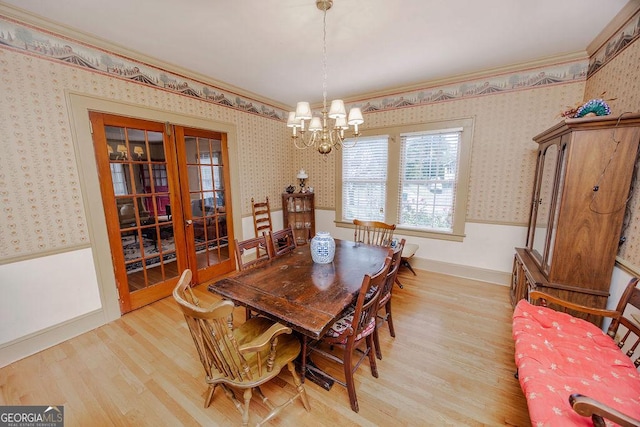 dining space featuring crown molding, french doors, a notable chandelier, and light wood-type flooring