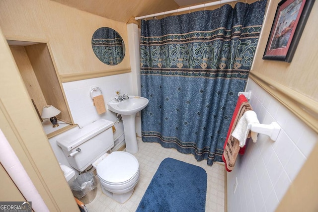 bathroom featuring toilet, sink, walk in shower, and tile walls