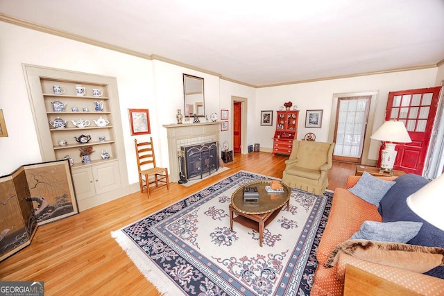 living room with built in features, wood-type flooring, and ornamental molding