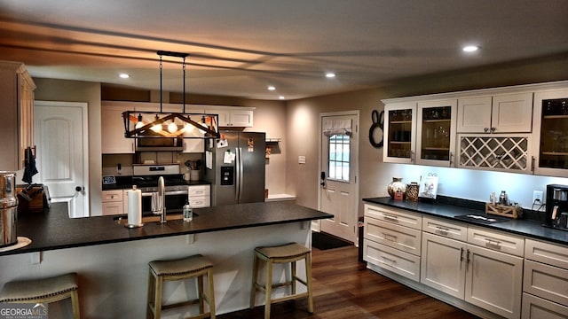 kitchen featuring appliances with stainless steel finishes, a breakfast bar area, decorative light fixtures, and white cabinets