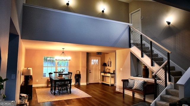 interior space with a towering ceiling, dark hardwood / wood-style flooring, and a notable chandelier