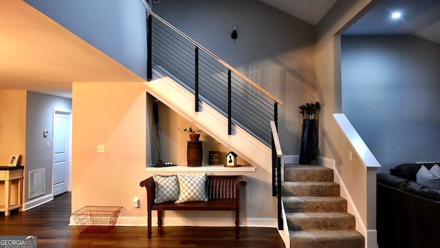 stairway with high vaulted ceiling and wood-type flooring