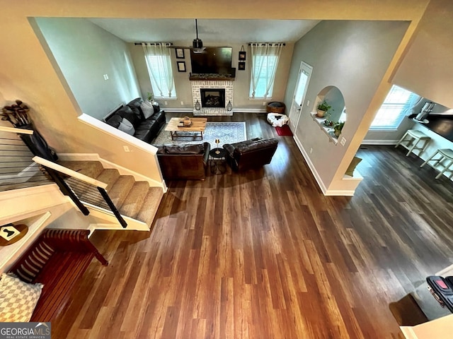 living room featuring a brick fireplace and wood-type flooring