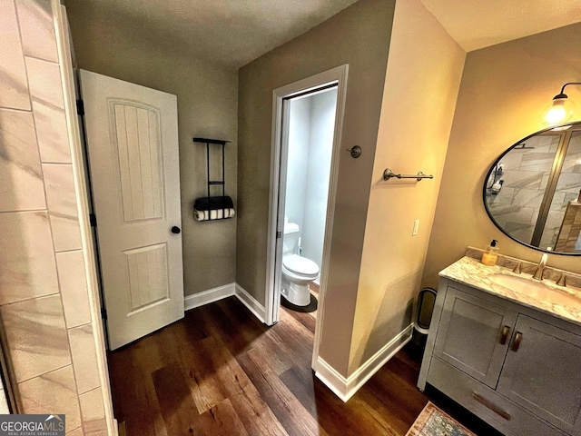 bathroom with vanity, toilet, and hardwood / wood-style flooring