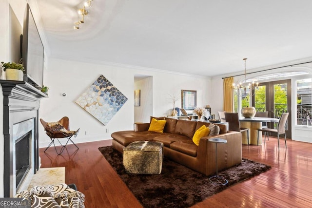 living room featuring a fireplace, ornamental molding, hardwood / wood-style flooring, and a notable chandelier