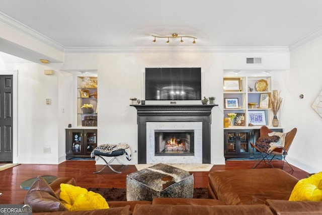 living room featuring ornamental molding, a high end fireplace, hardwood / wood-style floors, and built in features