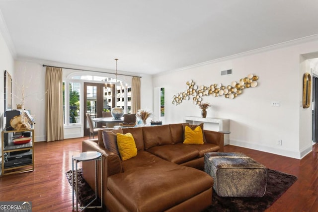 living room featuring ornamental molding, dark wood-type flooring, and an inviting chandelier