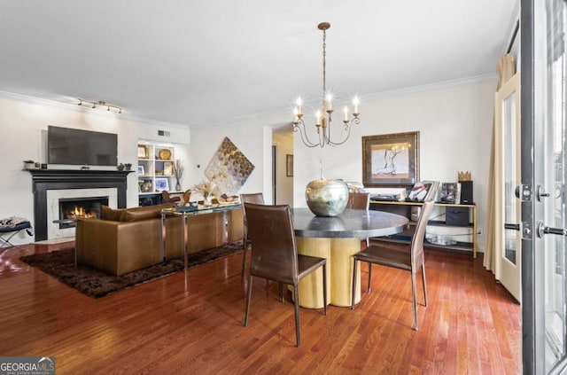 dining area with crown molding, a high end fireplace, wood-type flooring, and a chandelier