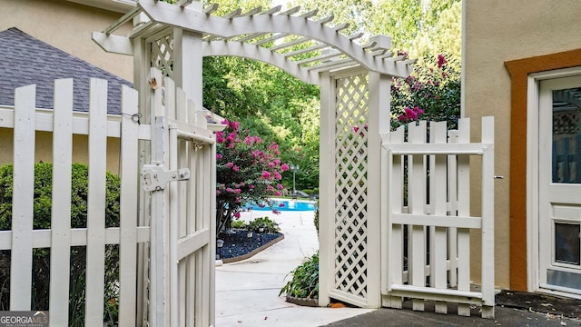 view of gate featuring a pergola and a swimming pool