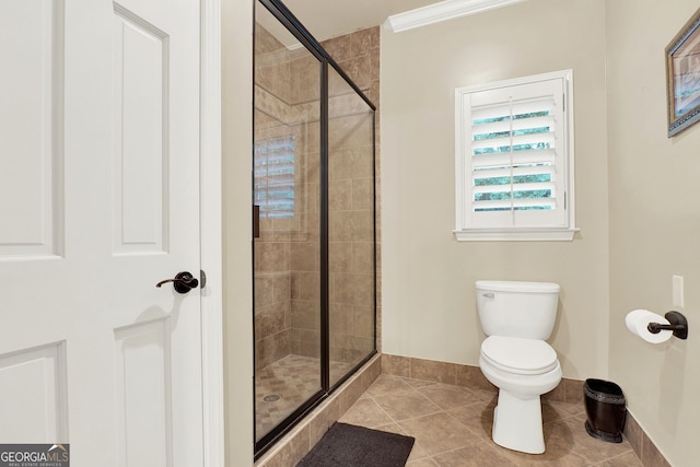 bathroom with toilet, crown molding, tile patterned floors, and walk in shower