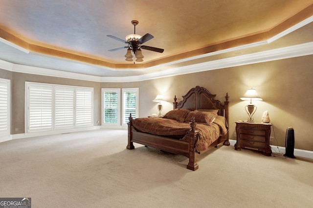 bedroom with ceiling fan, a tray ceiling, ornamental molding, and carpet flooring