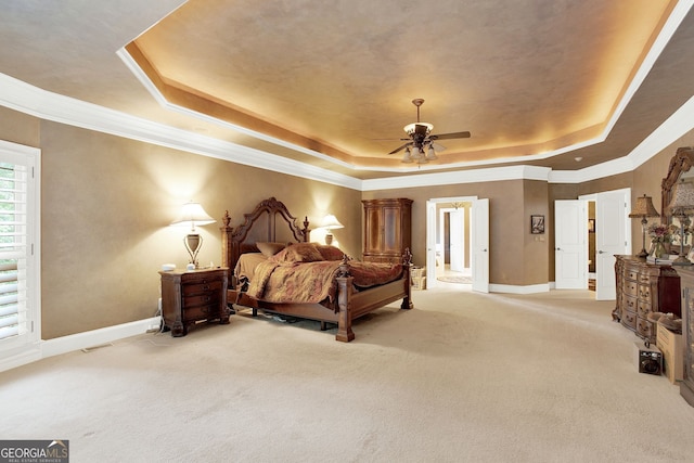 carpeted bedroom with ceiling fan, crown molding, and a tray ceiling