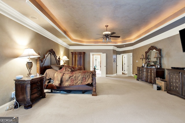 carpeted bedroom featuring ceiling fan, ornamental molding, and a tray ceiling