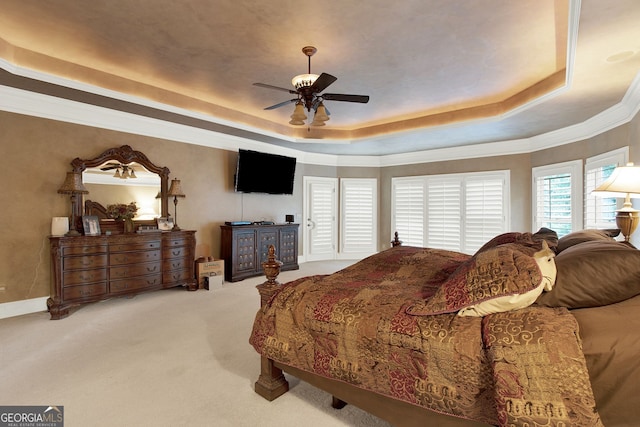 carpeted bedroom with ceiling fan, a tray ceiling, and ornamental molding