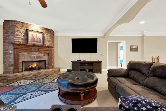 carpeted living room featuring ceiling fan, a stone fireplace, and ornamental molding