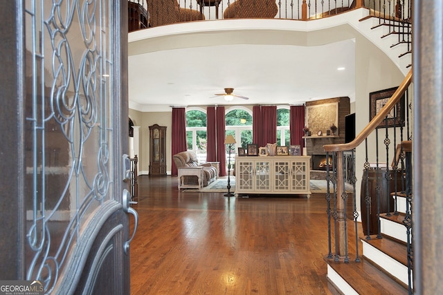 foyer entrance featuring ceiling fan, a fireplace, crown molding, and dark hardwood / wood-style floors