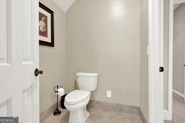 bathroom with toilet, vaulted ceiling, and tile patterned floors