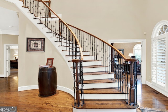 stairs featuring wood-type flooring and crown molding