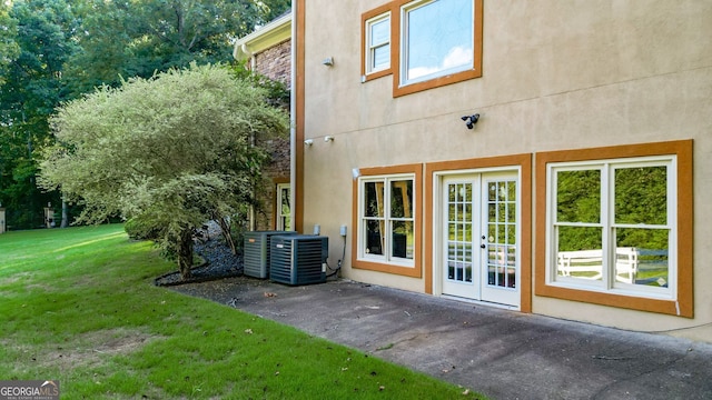 rear view of house with central air condition unit, french doors, and a yard