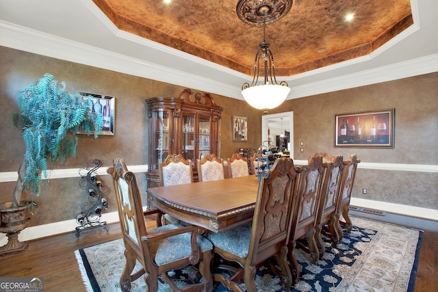 dining space with a tray ceiling, dark hardwood / wood-style floors, and ornamental molding