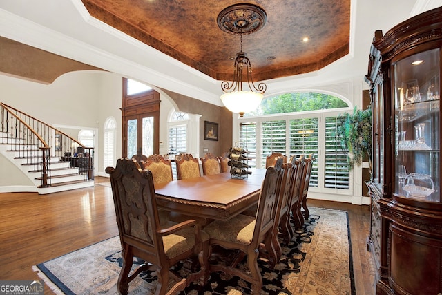 dining room featuring dark wood-type flooring, ornamental molding, and a raised ceiling