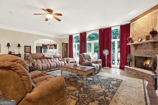 living room with a fireplace, ceiling fan with notable chandelier, ornamental molding, and hardwood / wood-style flooring