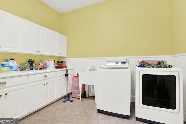 washroom with cabinets, light tile patterned floors, and washing machine and clothes dryer