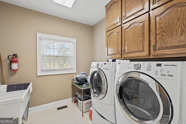 clothes washing area featuring cabinets and separate washer and dryer