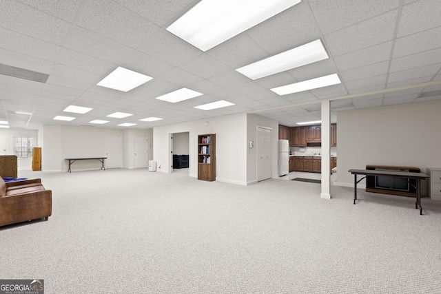 basement with a paneled ceiling and white refrigerator