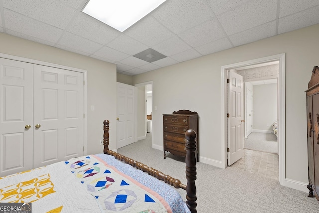 bedroom with a closet, light colored carpet, and a drop ceiling