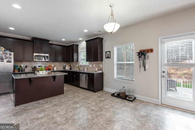 kitchen featuring a wealth of natural light, a center island, stainless steel appliances, and decorative light fixtures