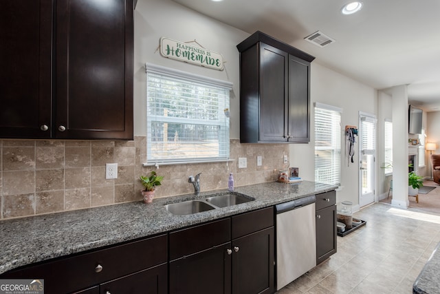 kitchen featuring tasteful backsplash, sink, stainless steel dishwasher, and light stone countertops