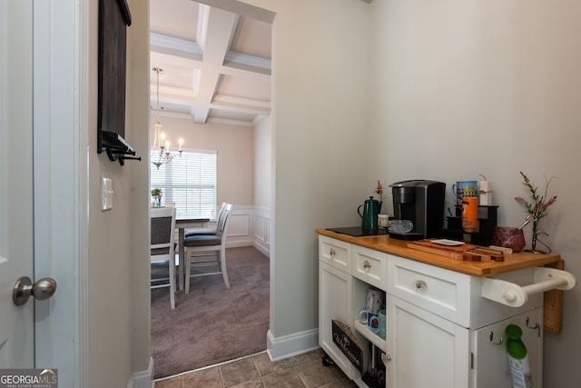 kitchen with coffered ceiling, beamed ceiling, a chandelier, butcher block countertops, and white cabinets