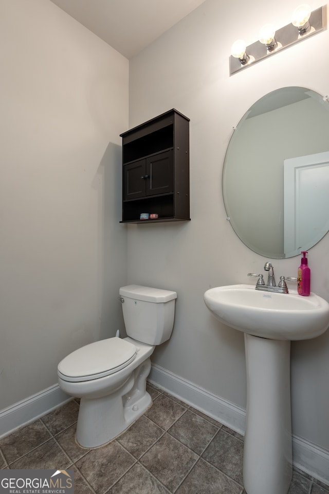 bathroom with toilet, sink, and tile patterned flooring