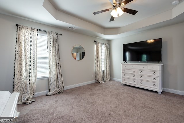 unfurnished bedroom featuring a raised ceiling, ceiling fan, and light carpet