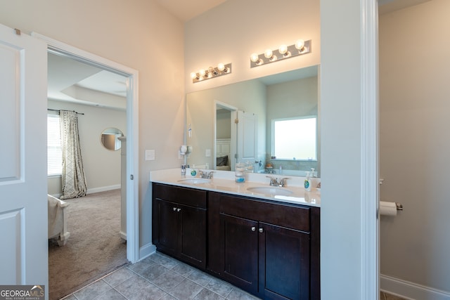 bathroom featuring a tray ceiling, vanity, a healthy amount of sunlight, and tile patterned floors