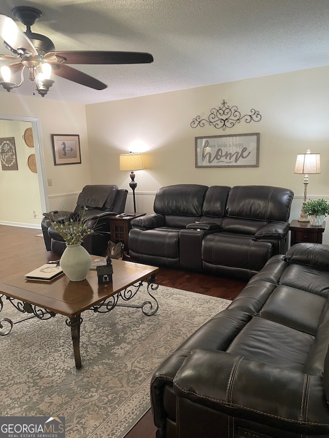 living room featuring a textured ceiling, ceiling fan, and dark wood-type flooring