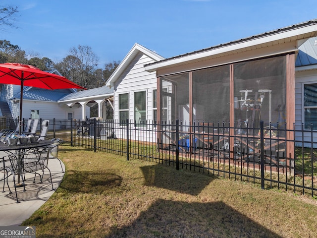 back of house featuring a patio area, a yard, and a sunroom