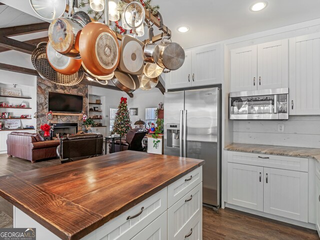 kitchen with a fireplace, butcher block countertops, dark hardwood / wood-style floors, appliances with stainless steel finishes, and white cabinets