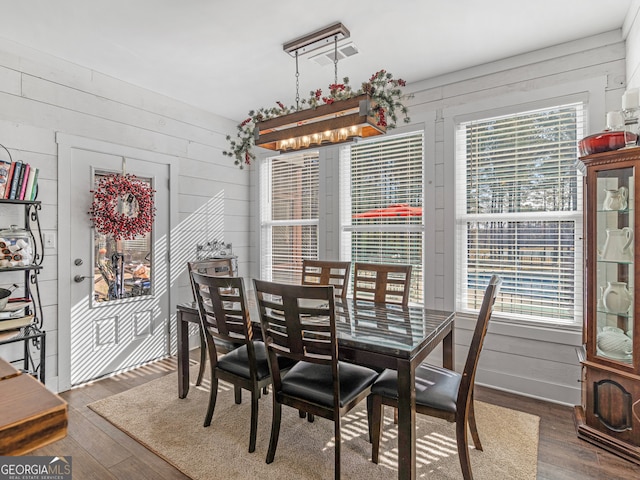 dining room featuring wood walls, a wealth of natural light, and dark hardwood / wood-style floors